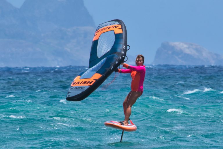A wing foiler sailing on a foiling board